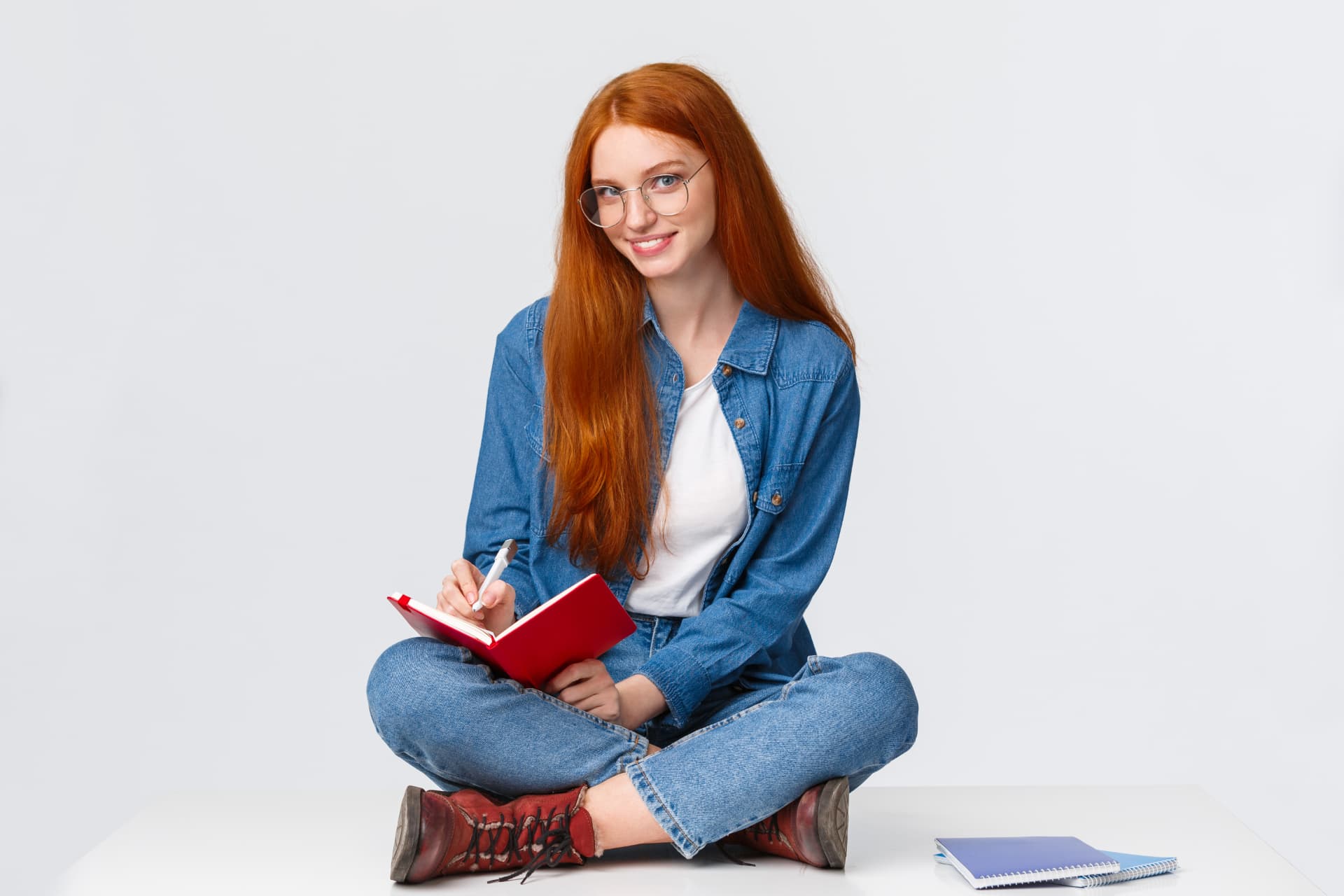 Student sitting cross-legged taking notes in a notebook